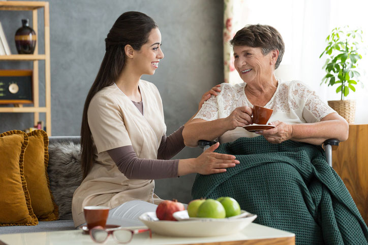 A nurse sits beside a senior woman at a dining facility in Shreveport, LA