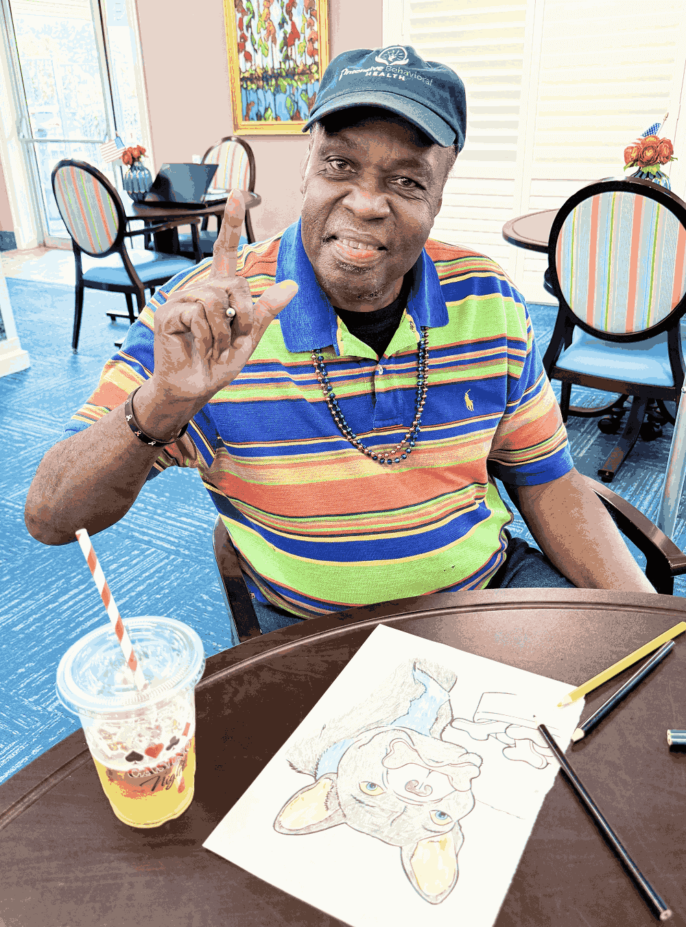 A man draws at a table in a dining facility showcasing his artistic focus in Shreveport, LA