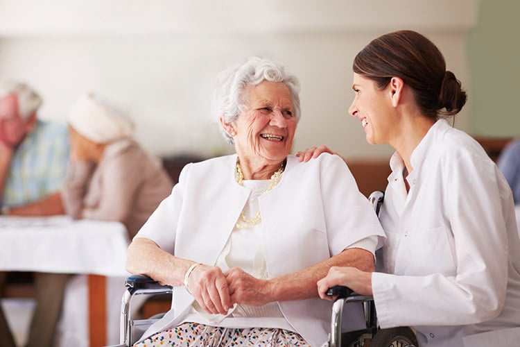 Elderly lady and nurse laugh together at skilled nursing facility