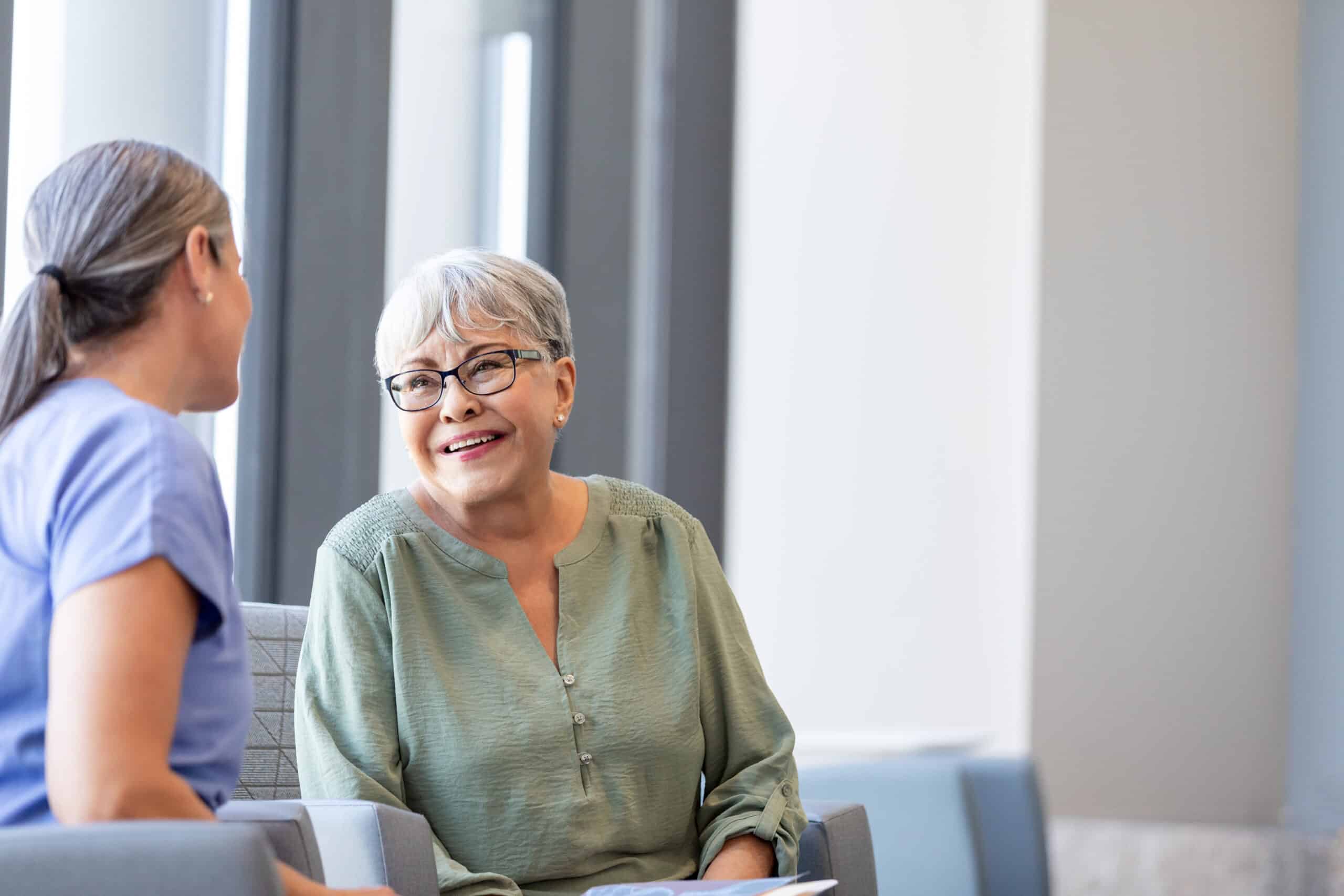 Speech therapist talks with senior woman at nursing facility
